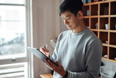 A man looking at the screen while holding a pen