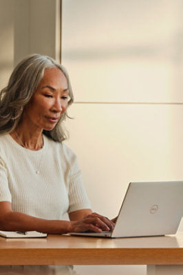 A woman having grey hair working on the laptop