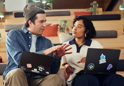 A man and woman discussing while holding a laptop