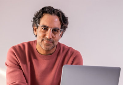 A man smiling sitting in front of the laptop
