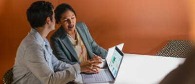 A man and woman looking at a laptop.