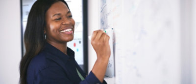 A woman writing something on the white board and smiling