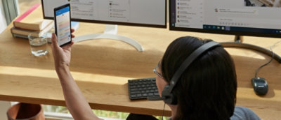 A person wearing headphones and looking at a mobile.