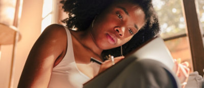 Close-up of a woman writing something on a book