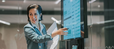 A person pointing at a screen while wearing a blue suit.