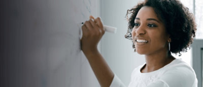 A woman wearing white top writing on the white board