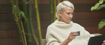 A person wearing a white sweater holding a phone.