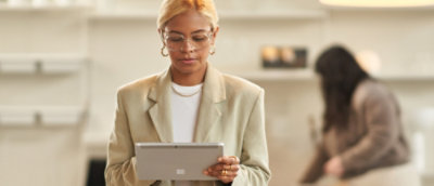 A woman wearing glasses and a suit holding a tablet
