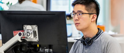 A person wearing glasses and headphones looking at a computer screen displaying the text OBS.