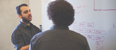 Two people discussing while looking at the white board