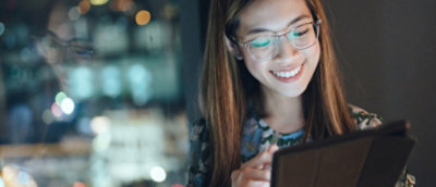 A close-up of a woman wearing glasses looking at the tablet