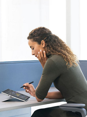 A person using a stylus on a tablet at a desk.