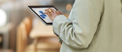 A woman standing using a tab.