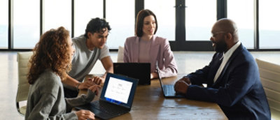 A group of people sitting around a table with laptops.