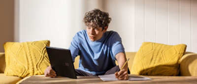 A person sitting at a table with a laptop and a pencil.