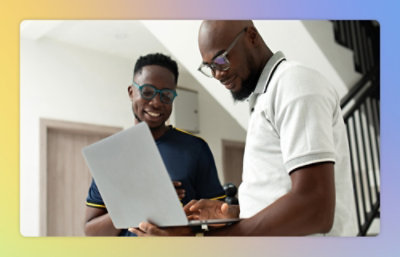 A man wearing glasses is sitting and looking at a laptop.