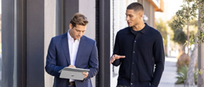 Two men in suits looking at a tablet.