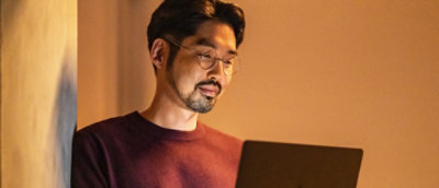 A person wearing glasses looking at a laptop.