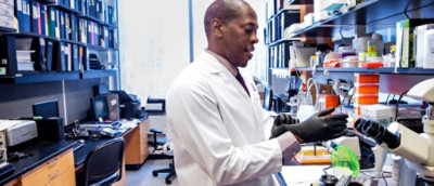 Seorang pria yang mengenakan jas lab dan sarung tangan.