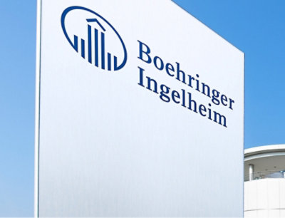 white sign with blue text reading Boehringer Ingelheim against a building wall.