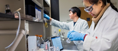 A few people in a lab wearing white lab coats.