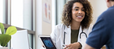 A Doctor in a white coat holding a tablet.