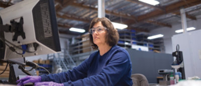 A woman wearing glasses sitting at a computer.