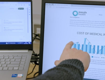 A hand pointing at a graph on a computer screen with partially visible text.