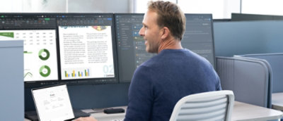 A man looking at a computer screen with multiple monitors visible.