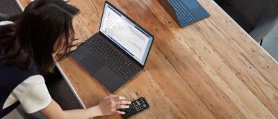 A person using a laptop on a wooden table.