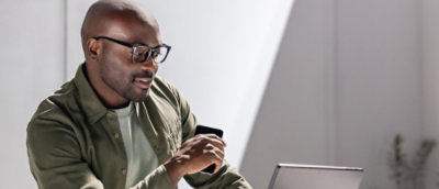 Un hombre con gafas y una camiseta verde mirando un portátil.