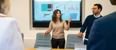 Una mujer de pie delante de una pantalla grande.