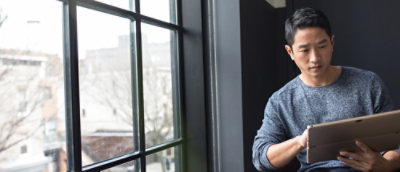 A person sitting beside the window and looking at the tablet