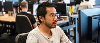 A man wearing glasses working on the laptop