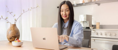 A woman working on the laptop with a vase beside her laptop