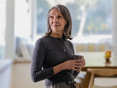 A woman holding a cup, looking away and smilling