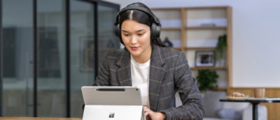 Une femme portant des écouteurs et regardant une tablette.