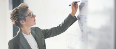 A woman writing something on the white board and smiling