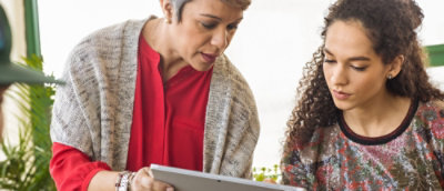 Two individual discussing while looking at the tablet.