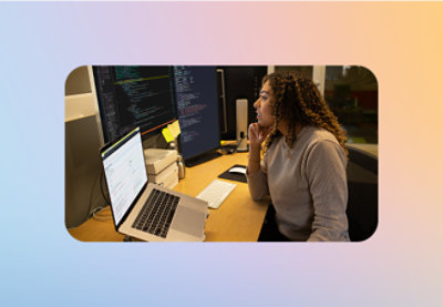 A women looking at the laptop and screens attached to the laptop.