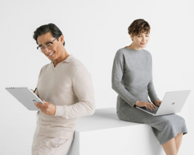 Two adults work on their devices against a white background. One stands with a tablet and stylus