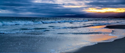 A beach with waves and a sunset