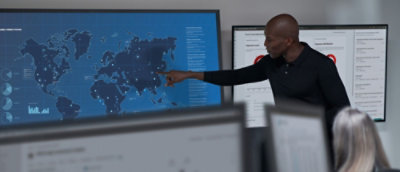 A man showing smoething to a women on big screen.