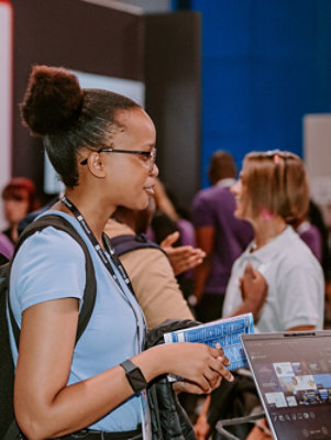 A person holding a blue book next to a laptop with text visible.