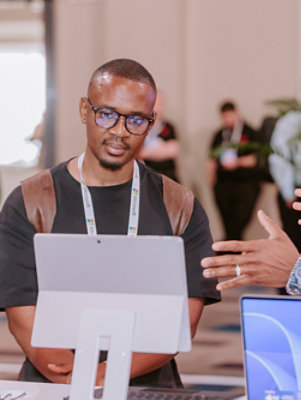 A person standing at a table with a laptop in a blue and white setting.