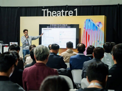 A man standing in front of a group of people with Theatre 1 visible in the background.