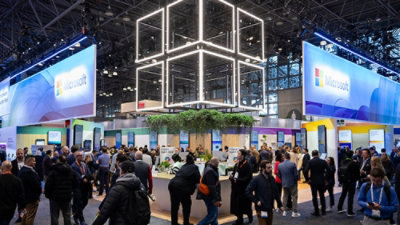 A group of people standing in front of a counter with a glass cube with lights nearby and text Microach visible.