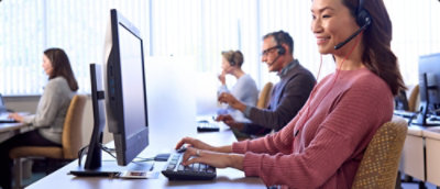 A person wearing a headset and sitting at a desk with a computer.