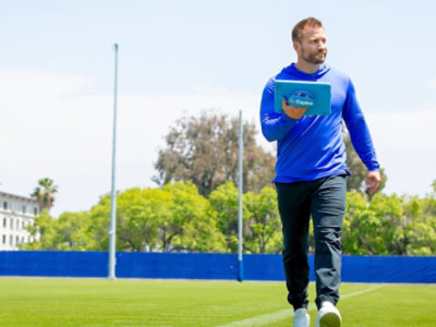  A person walking on ground with a tab in hand. 