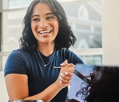 Two men conversing in an office with large windows overlooking a cityscape. 